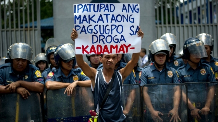 ناشط يرفع لافتة امام الشرطة الفيليبينة خلال تظاهرة منددة بعمليات القتل على خلفية حملة الرئيس رودريغو دوتيرتي لمكافحة المخدرات، في مانيلا في 24 آب/اغسطس 2016