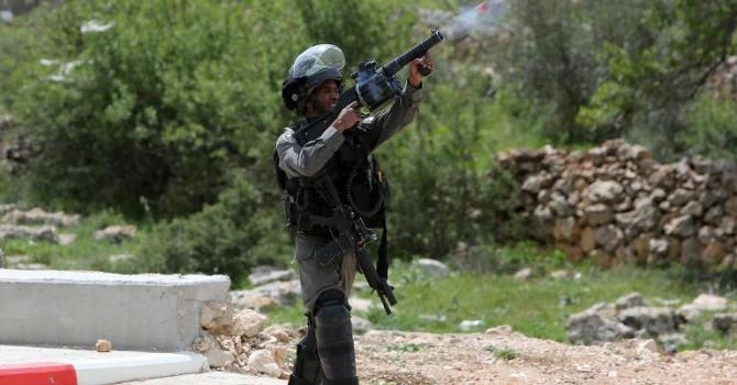 جندي اسرائيلي يطلق الغاز المسيل للدموع على متظاهرين فلسطينيين في سلواد، شمال رام الله بالضفة الغربية، في 30 آذار/مارس 2015