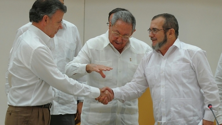 الرئيس الكولومبي خوان مانويل سانتوس (يسار) مصافحا زعيم حركة فارك تيموليون خيمينيث (يمين) امام الرئيس الكوبي راوول كاسترو في 23 ايلول/سبتمبر 2015